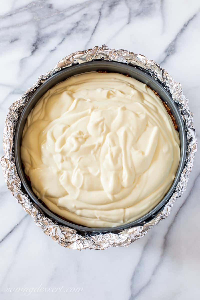 Overhead view of a springform pan wrapped in foil and filled with cheesecake batter