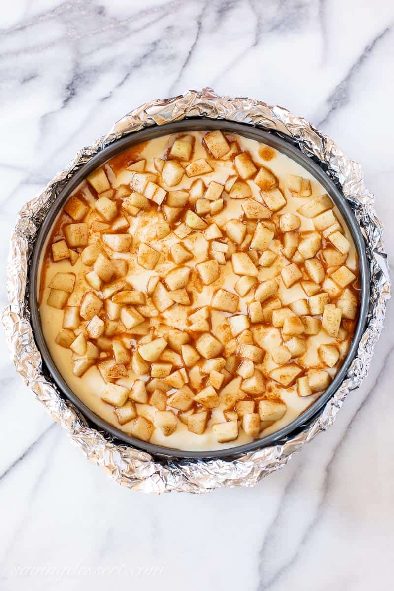 Overhead view of an unbaked cheesecake topped with diced cinnamon apples