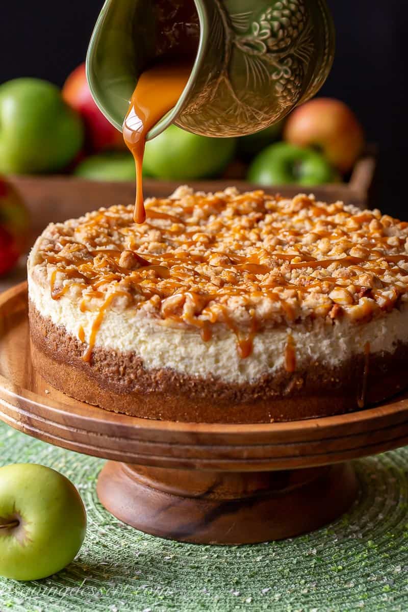 Caramel being drizzled on a caramel apple cheesecake with crumble topping
