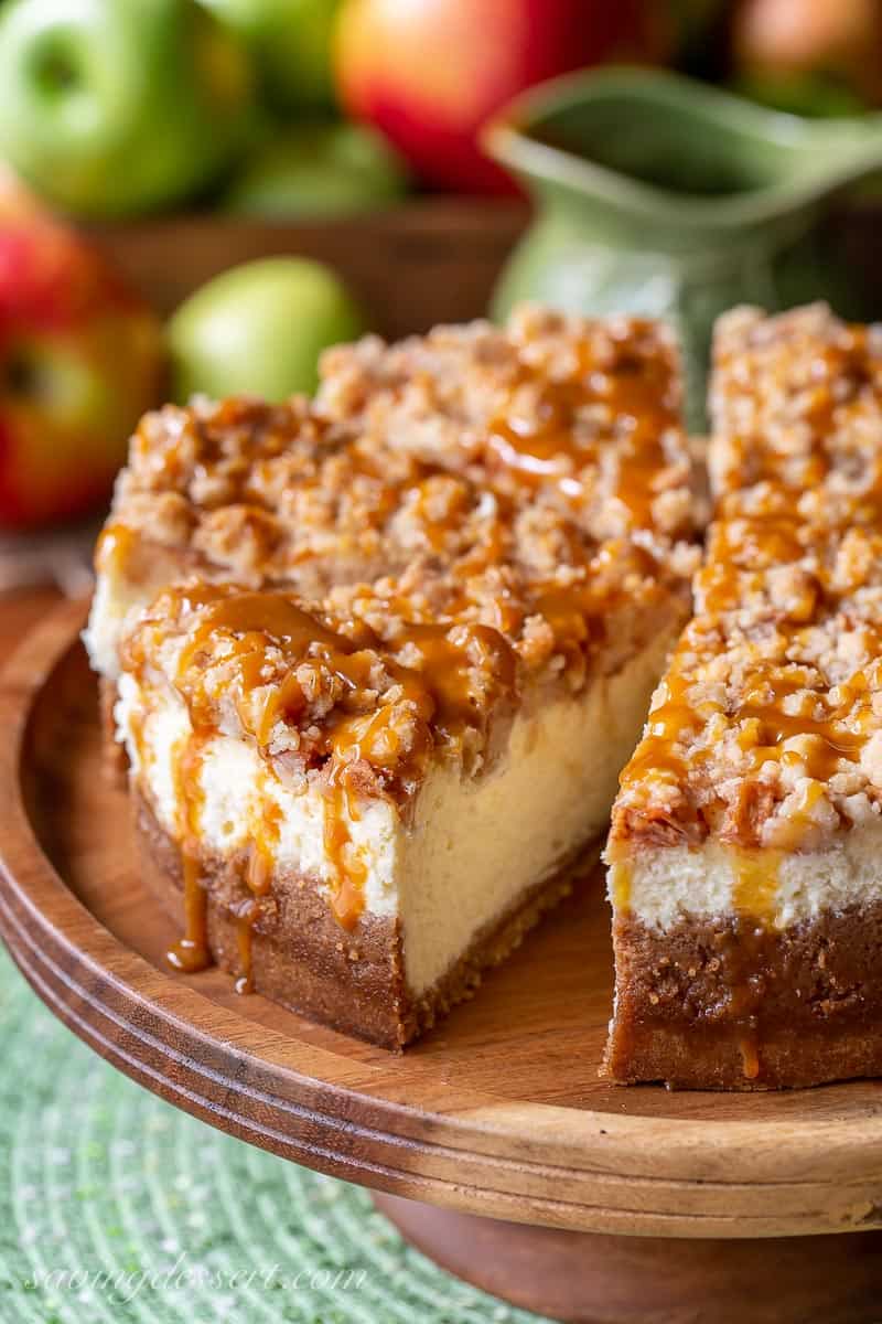 A sliced caramel apple cheesecake on a cake stand