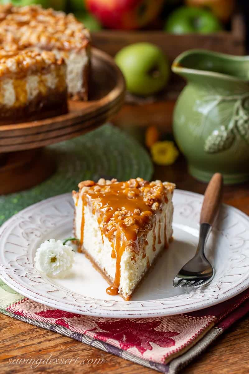 A slice of caramel apple cheesecake with caramel sauce dripping down the sides