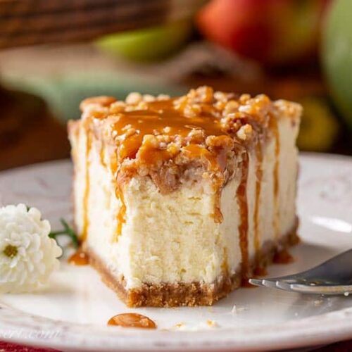 A close up of a partially eaten slice of caramel apple cheesecake with caramel dripping down the sides.