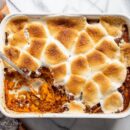 Overhead view of a casserole dish filled with sweet potatoes topped with melted, golden brown toasted marshmallows