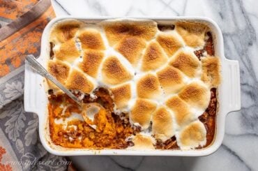 Overhead view of a casserole dish filled with sweet potatoes topped with melted, golden brown toasted marshmallows