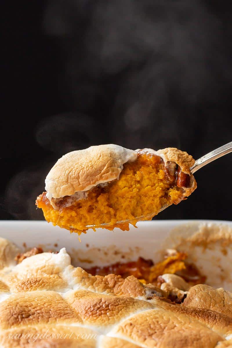 A spoon filled with hot steaming sweet potato casserole