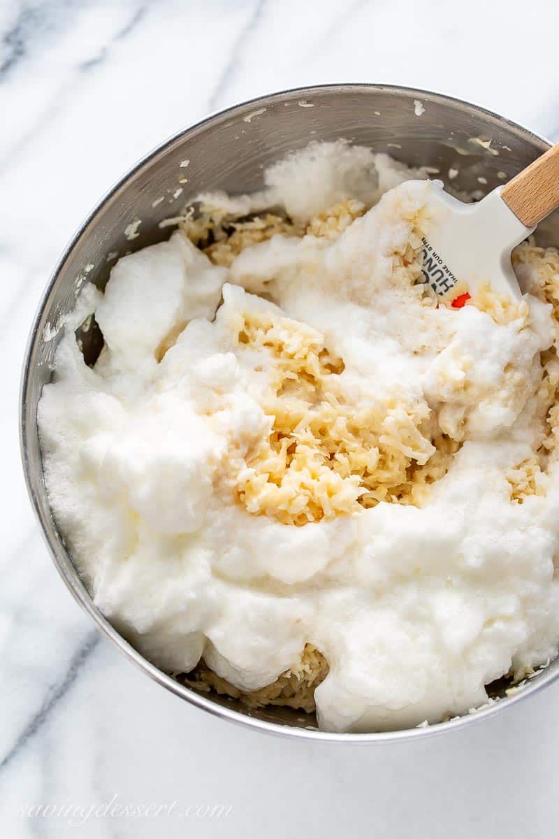 A mixing bowl filled with whipped egg whites and a coconut mixture