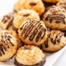 Closeup of a platter of golden brown coconut macaroons dipped and drizzled in chocolate
