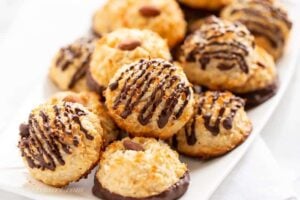 Closeup of a platter of golden brown coconut macaroons dipped and drizzled in chocolate