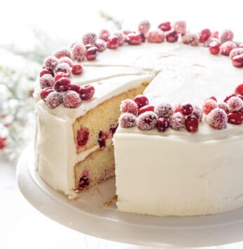 A sliced cranberry cake topped with sugared cranberries