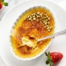 Overhead view of a small shallow dish filled with Creme Brûlée, pistachios and a spoon