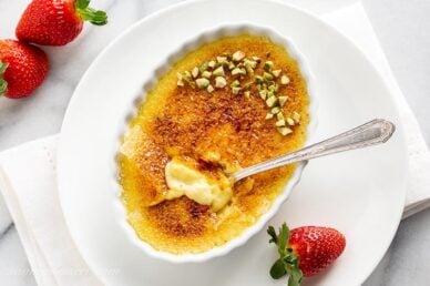 Overhead view of a small shallow dish filled with Creme Brûlée, pistachios and a spoon