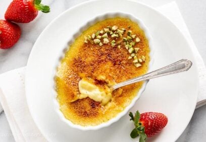 Overhead view of a small shallow dish filled with Creme Brûlée, pistachios and a spoon