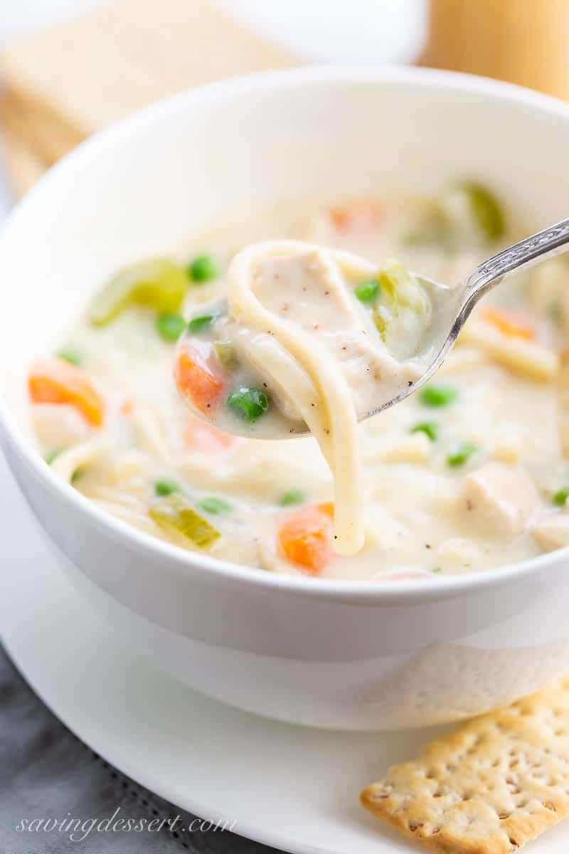 a spoonful of creamy noodle soup with crackers