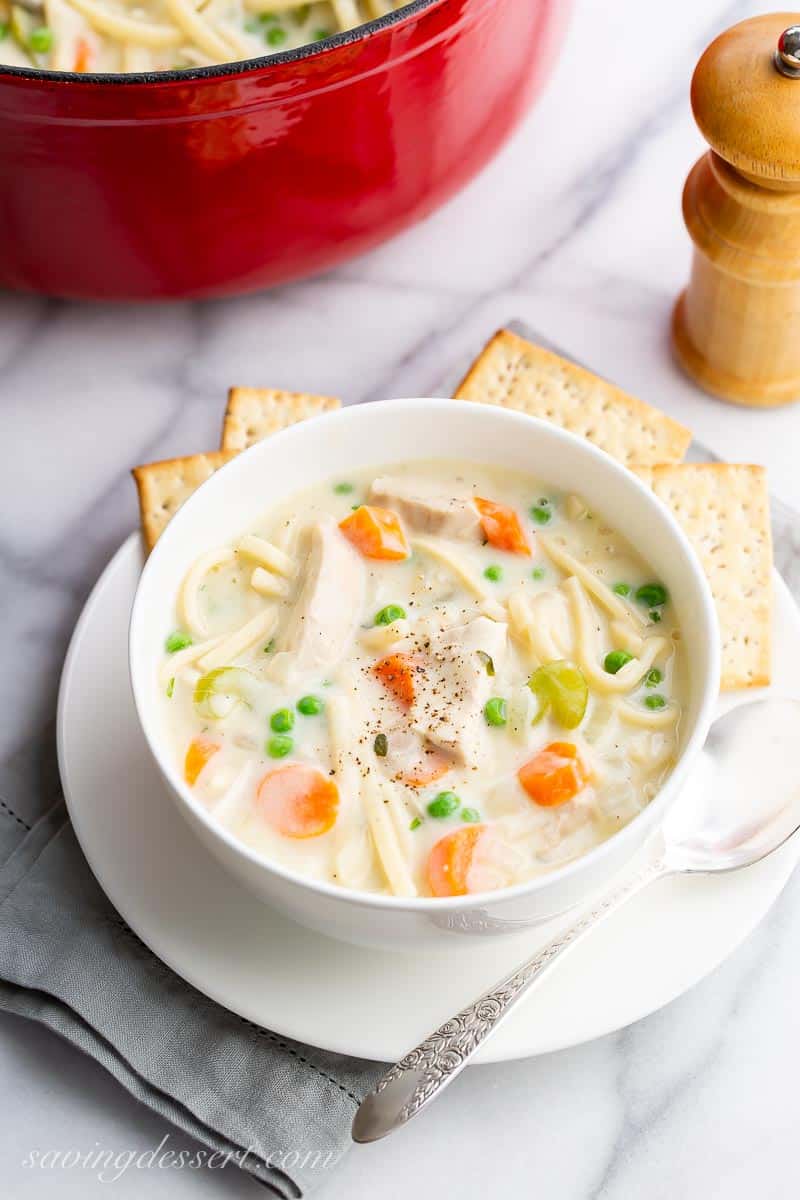 A bowl of soup on a counter top with a Dutch oven pot filled with soup