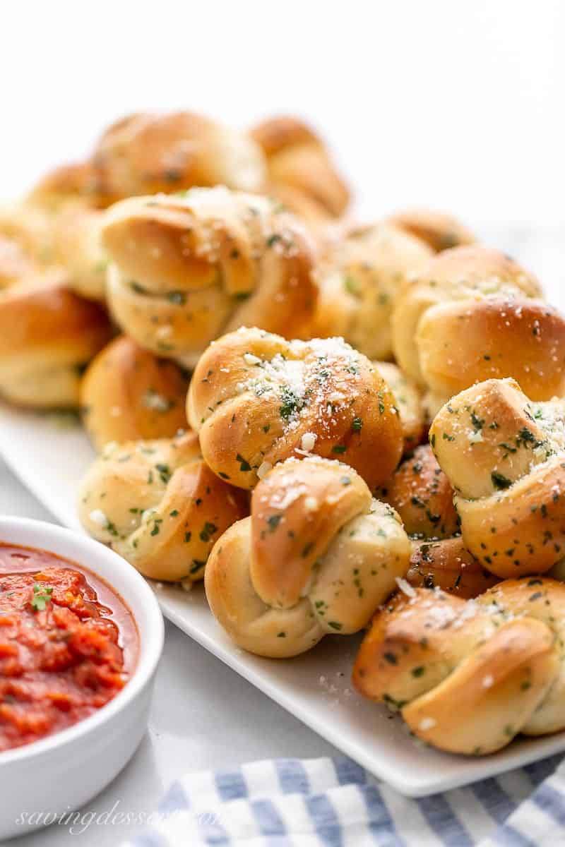 Buttery twists of golden pizza dough on a platter with a bowl of marinara