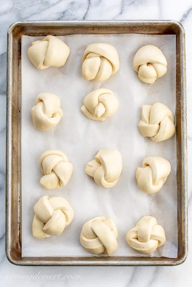 Puffy pizza dough knots on a baking pan