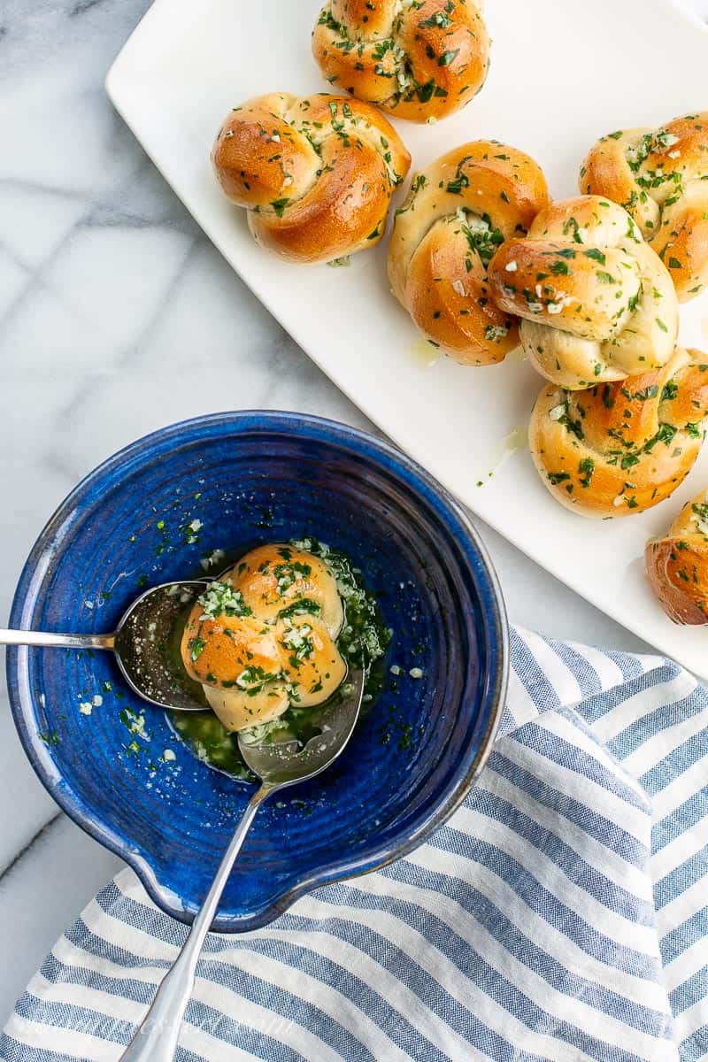 Baked pizza knots being tossed in a butter garlic mixture