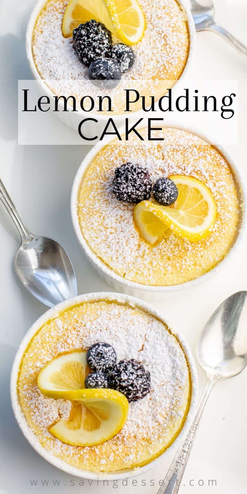 Overhead view of three ramekins filled with Lemon Pudding Cake garnished with powdered sugar, lemon slices and berries