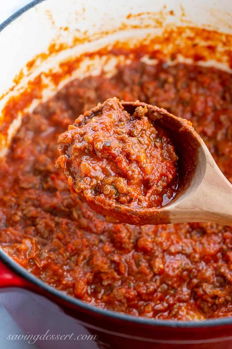 A ladle filled with meaty red tomato sauce