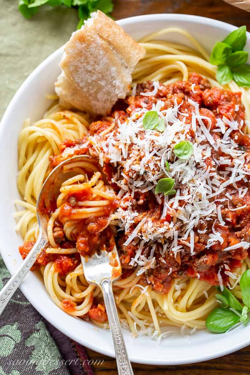 A fork and spoon with twirls of spaghetti noodles covered in a rich red tomato sauce