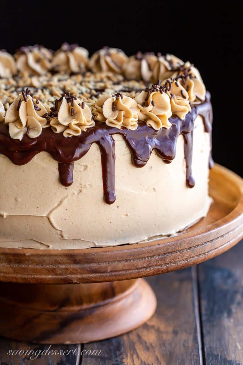 Peanut butter frosting over a chocolate layer cake with drips of ganache and swirls of icing to decorate
