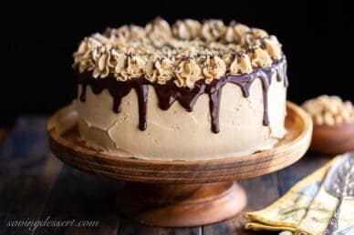 A peanut butter frosted chocolate cake with chocolate ganache dripping down the sides