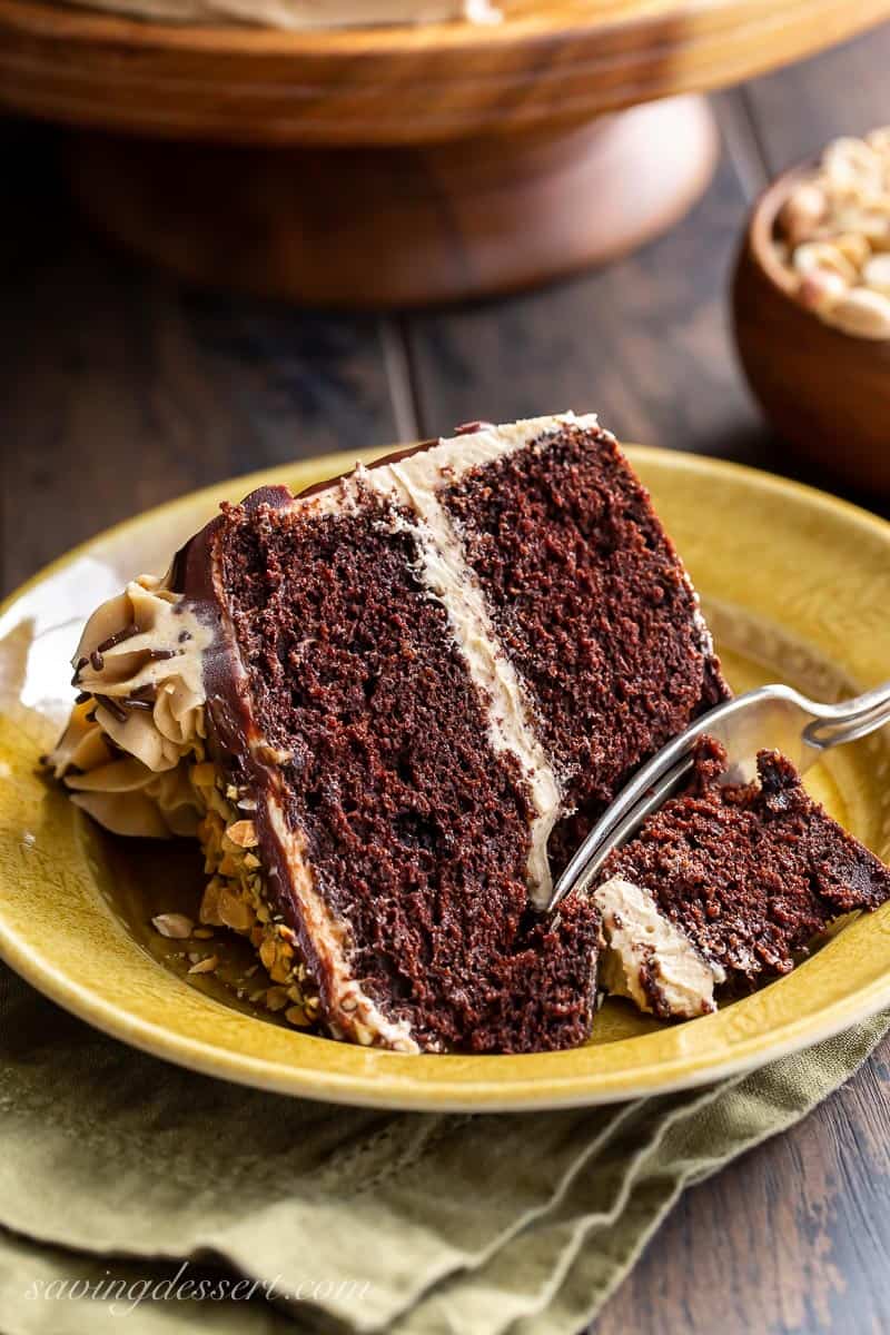 A fork slicing a piece of chocolate cake with peanut butter frosting