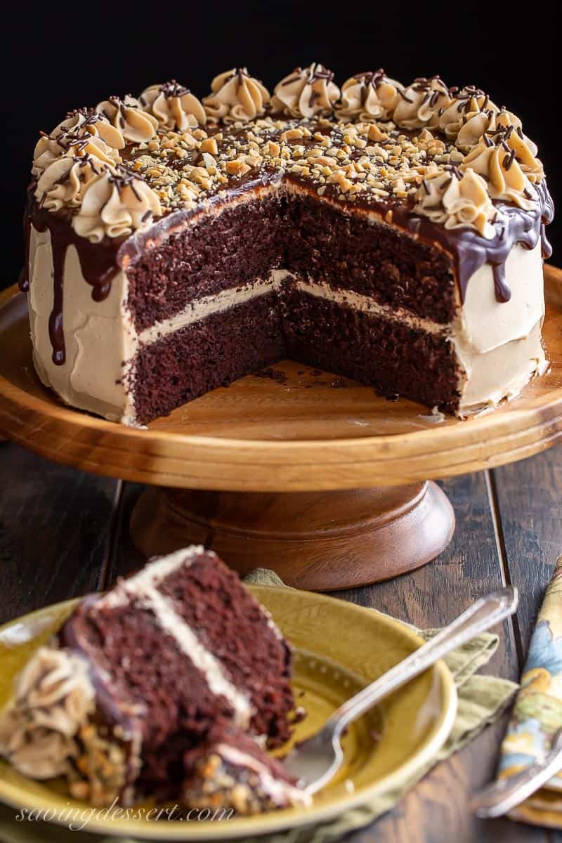 A chocolate cake on a cake stand showing the inside and decorated with peanut butter frosting