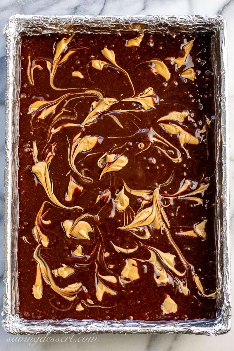 Brownie batter in a pan with swirls of peanut butter on top