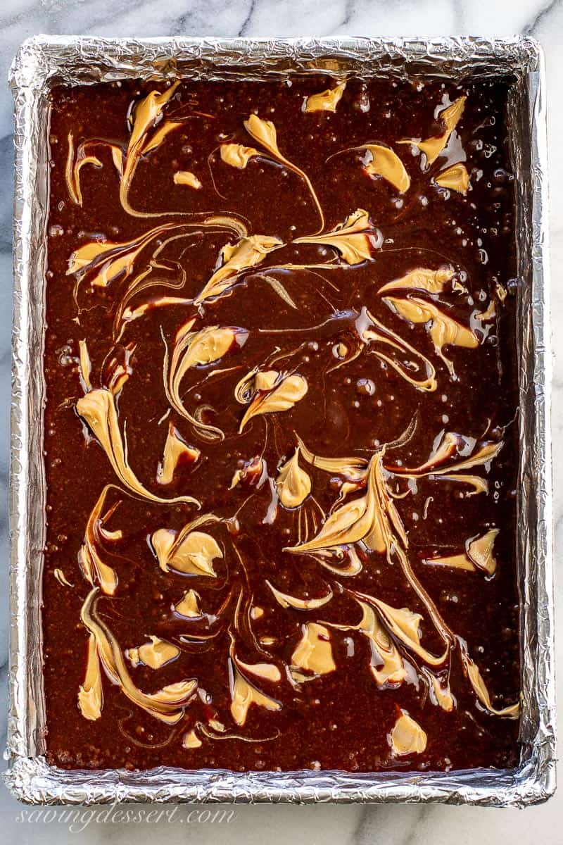 Brownie batter in a pan with swirls of peanut butter on top