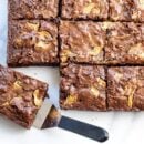 Overhead view of brownies cut into squares with one on a spatula