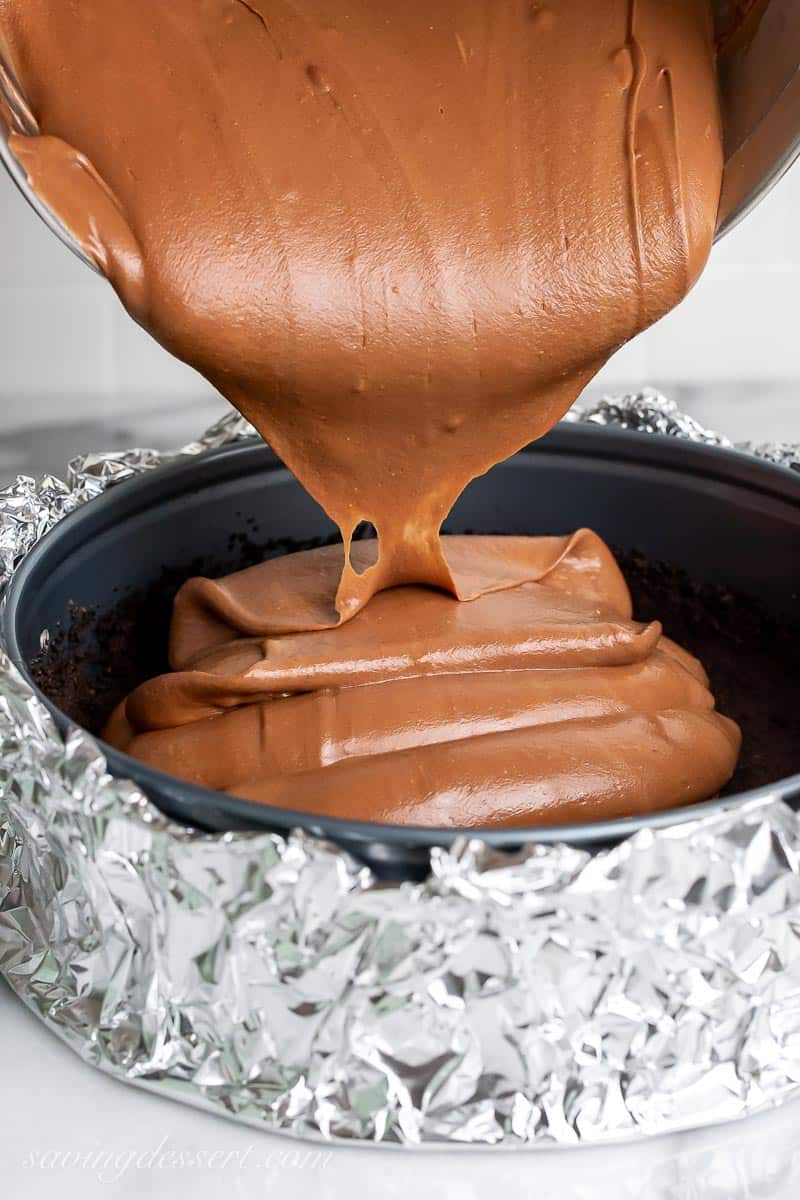Cake batter being poured into a foil wrapped springform pan