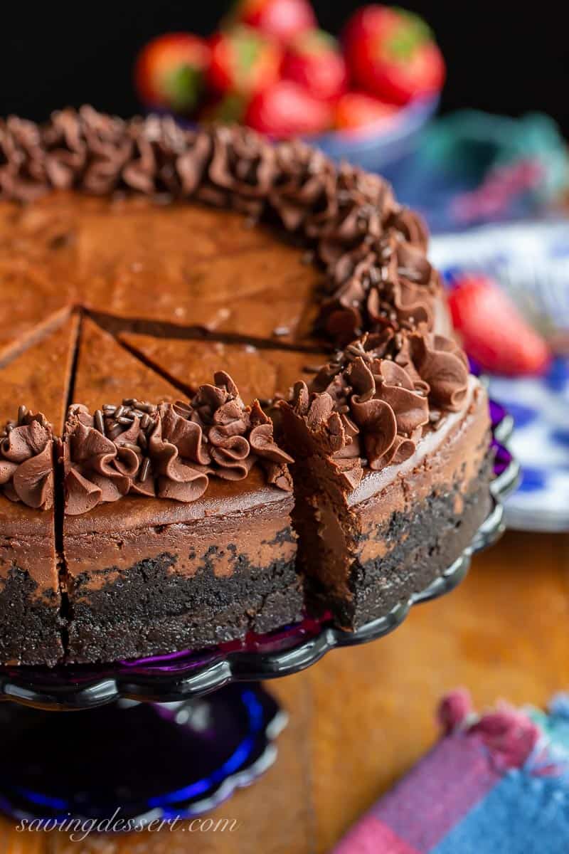 A sliced chocolate cheesecake topped with swirls of whipped chocolate ganache
