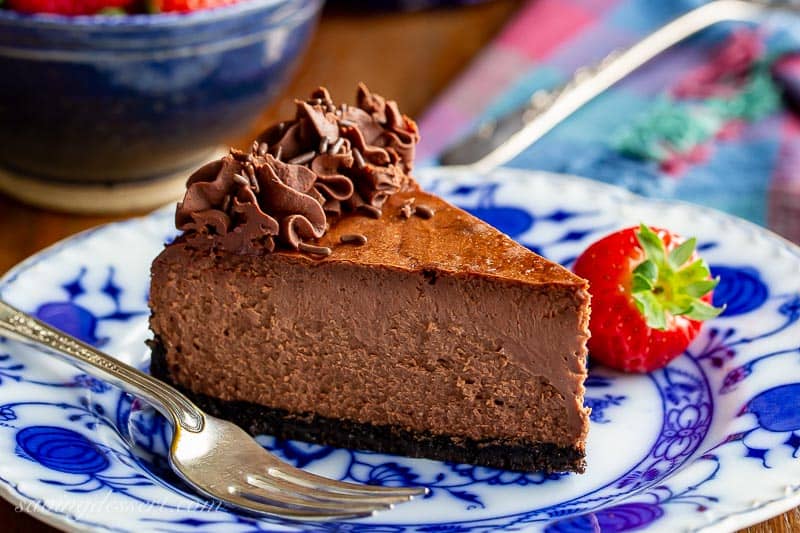 Chocolate cheesecake with a swirl of whipped chocolate ganache on a plate with strawberries