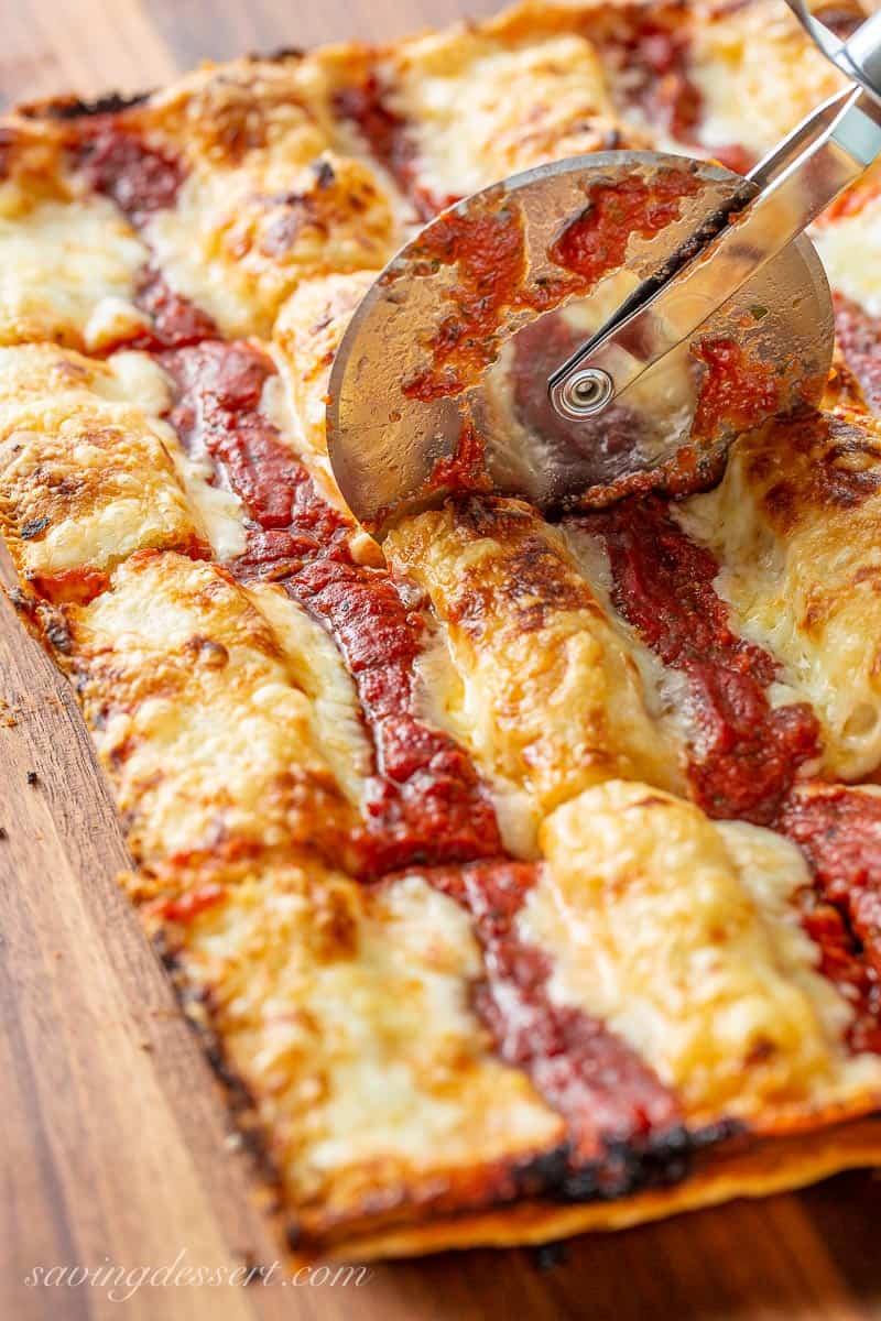 A pizza cutter going through a thick crust pizza