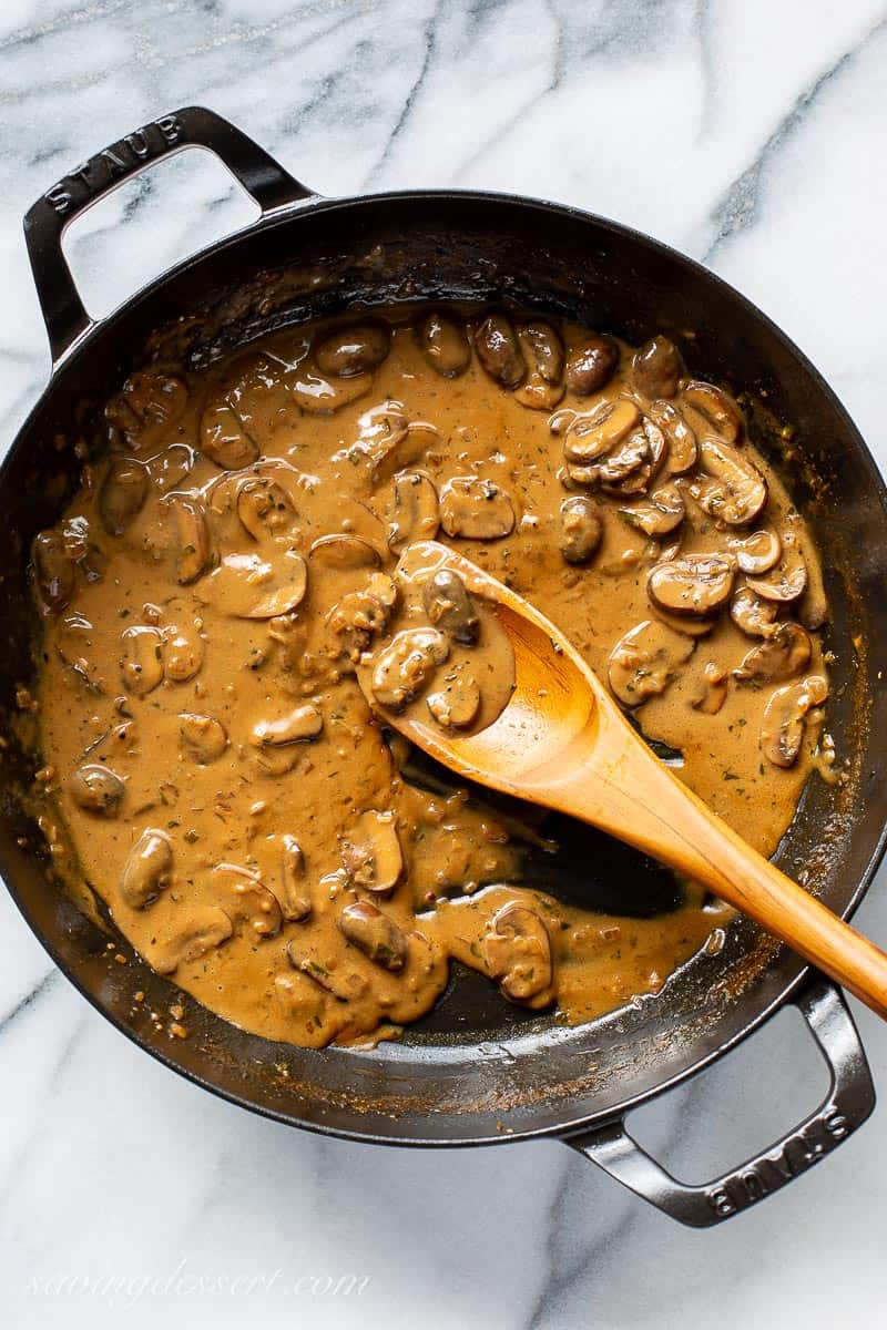 A skillet filled with golden brown mushroom sauce for steak