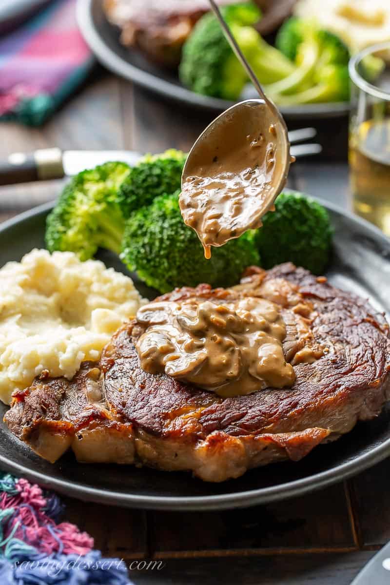 Mushroom sauce for steak being ladled over a ribeye steak on a plate