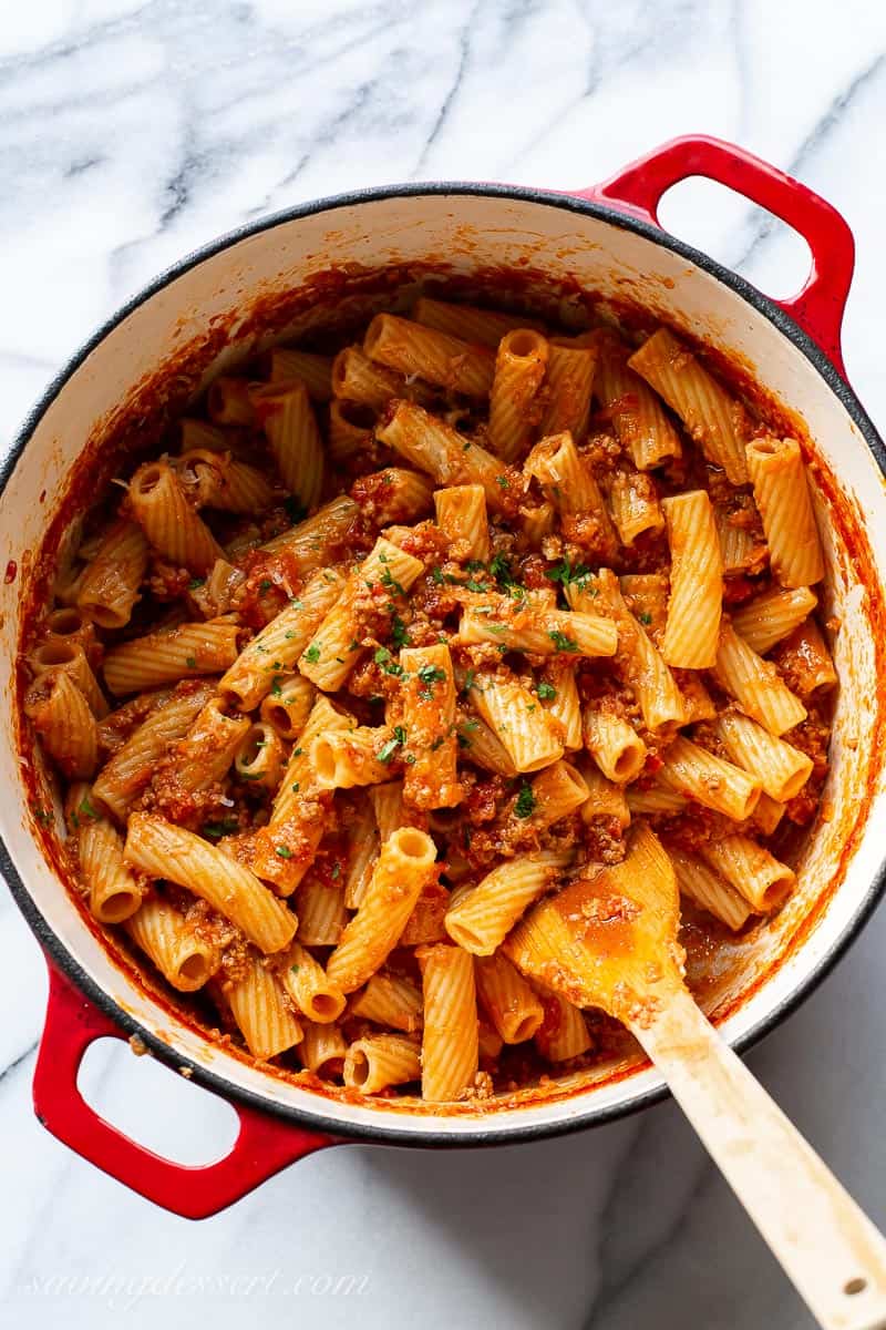 Rigatoni pasta covered in a tomato meat sauce in a Dutch Oven pot