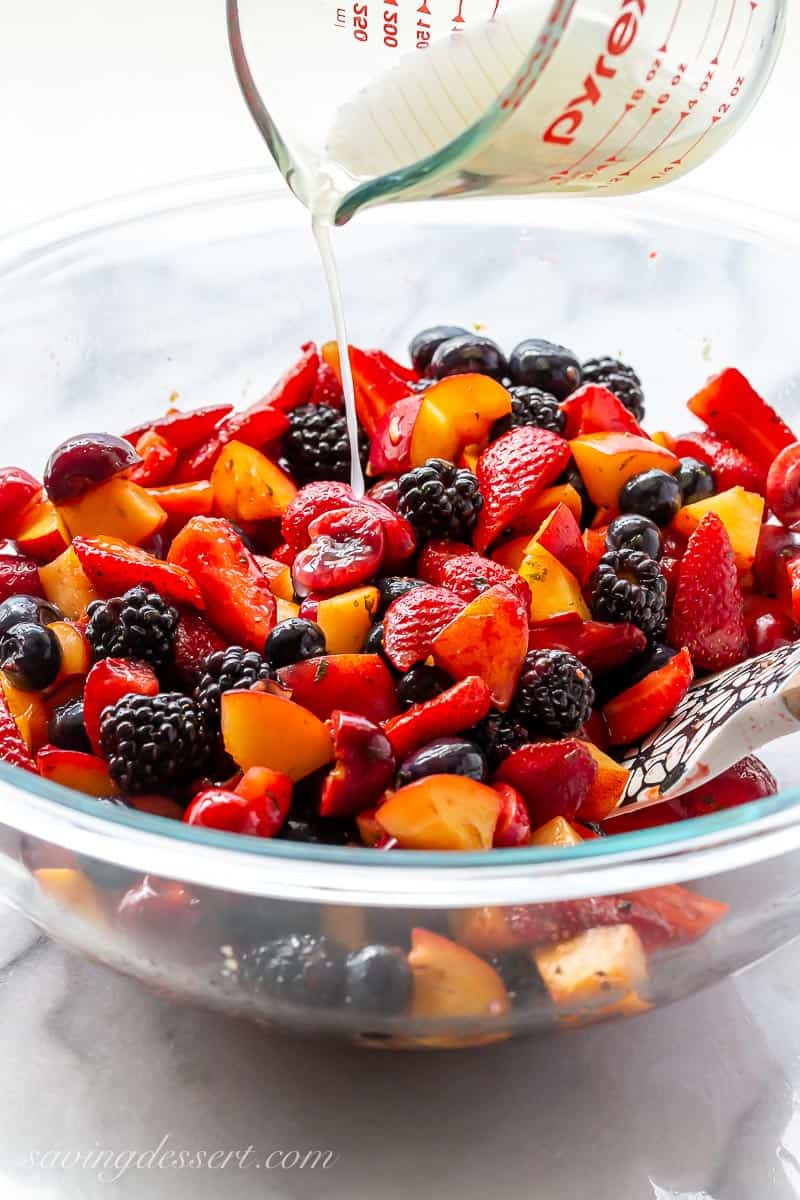 A bowl of fresh fruit and berries being drizzled with lime juice