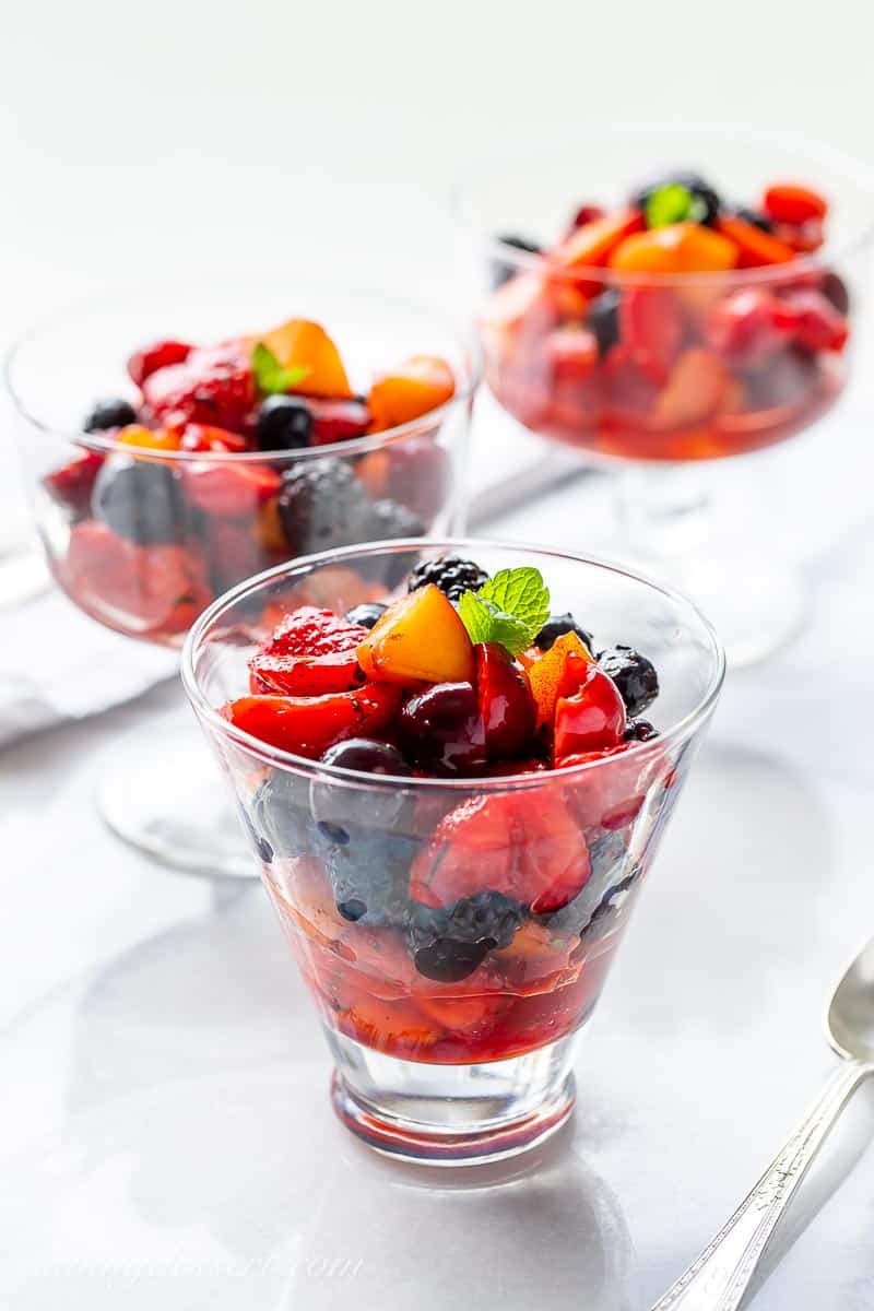 Dessert dishes filled with fresh fruit salad and a garnish of fresh mint leaves
