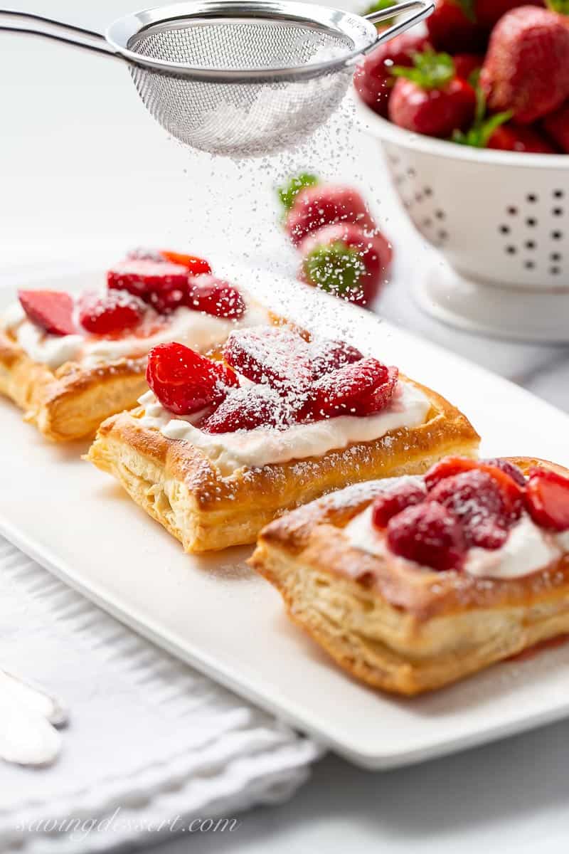 Strawberry tarts being dusted with powdered sugar