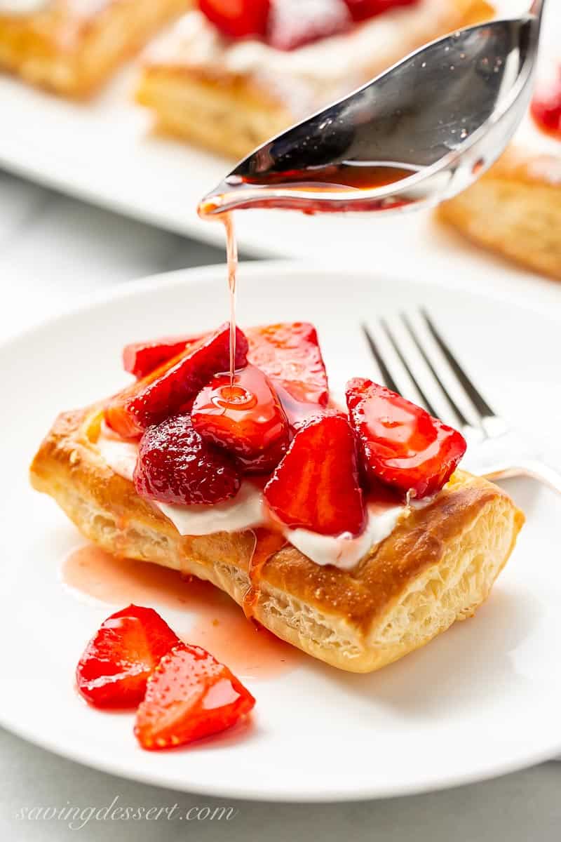 A strawberry puff pastry tart being drizzled with strawberry syrup