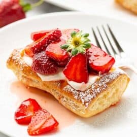 A strawberry tart on a plate with a fork