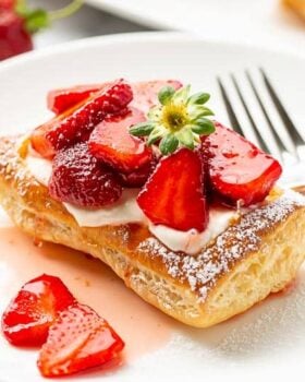 A strawberry tart on a plate with a fork