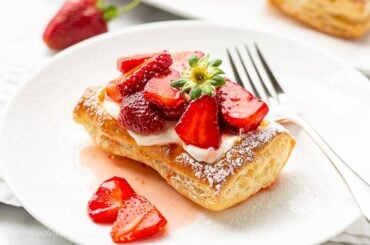 A strawberry tart on a plate with a fork
