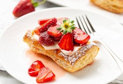 A strawberry tart on a plate with a fork