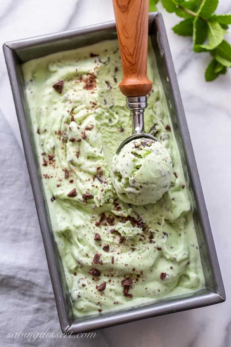 An ice cream scoop in a pan of mint chocolate chip ice cream