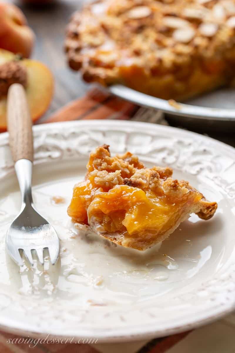 A small bite of peach crumble pie leftover on a plate with a fork