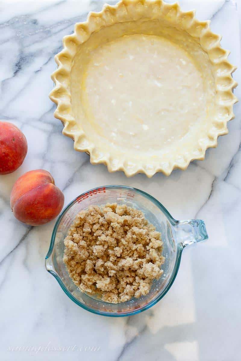 An unbaked pie crust and a bowl of crumble topping