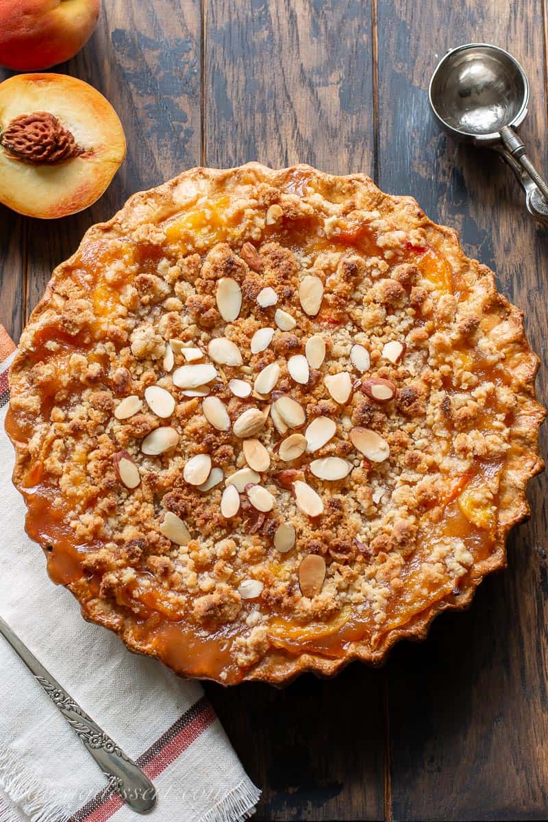 A baked peach crumble pie with almonds on top
